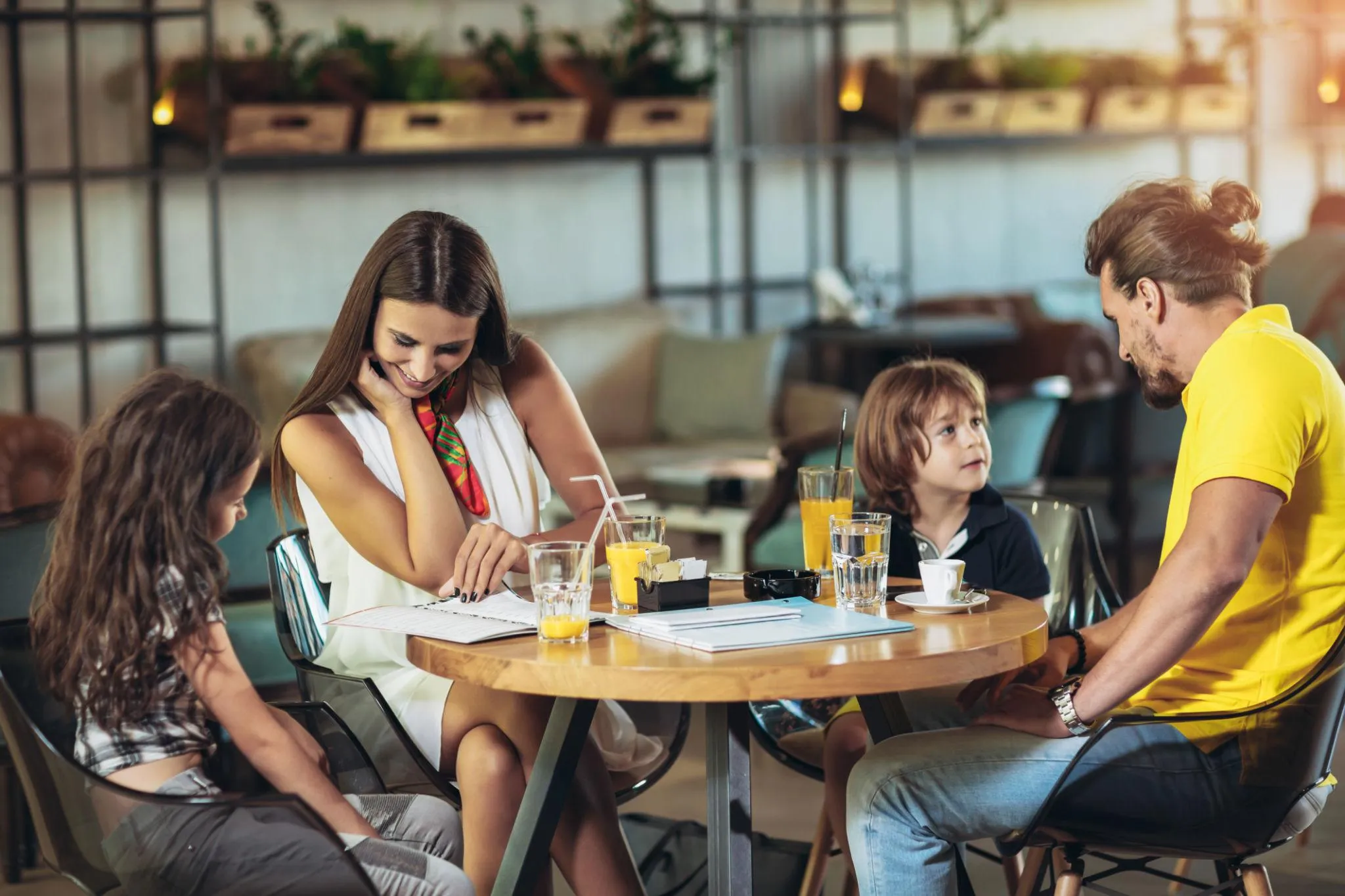 A family of four sitting around a restaurant table talking over drinks
