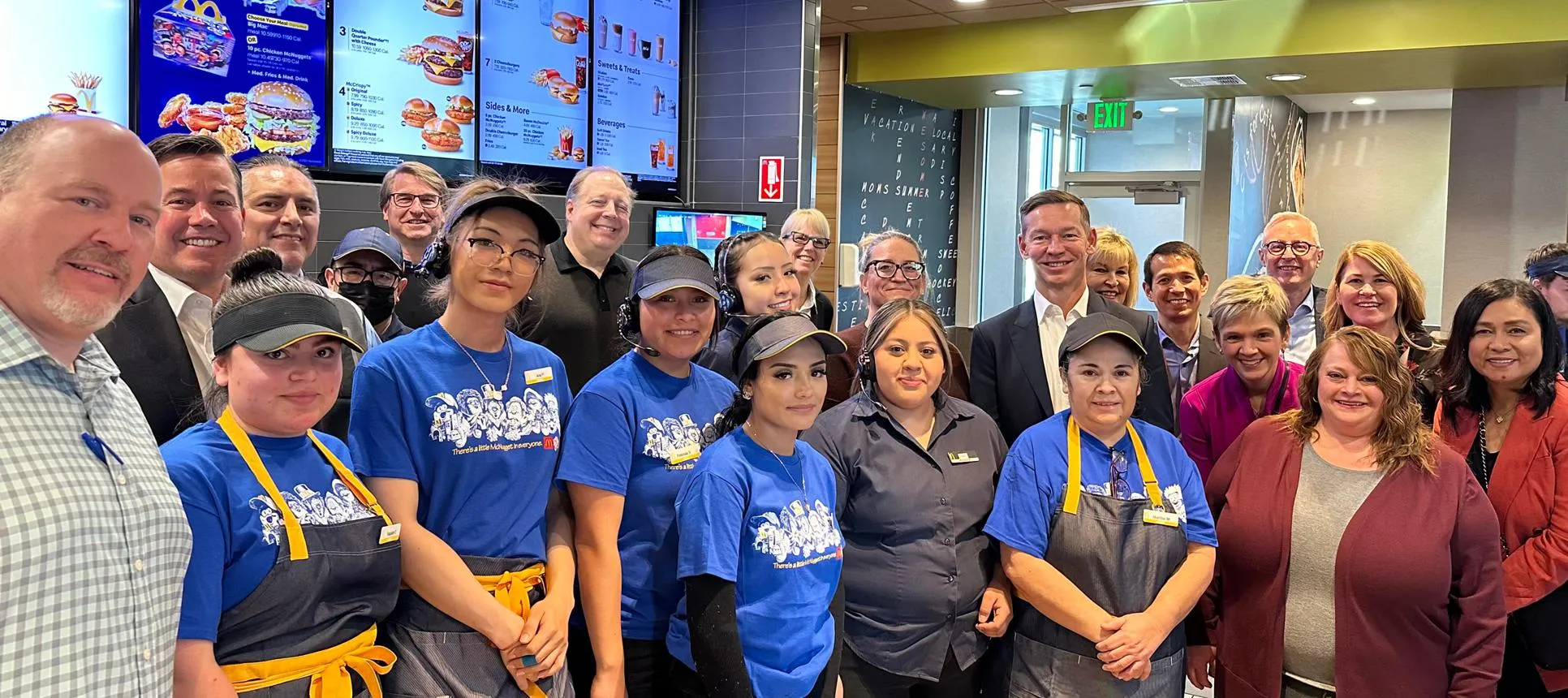 A large group of corporate executives and restaurant staff posing together inside a McDonalds