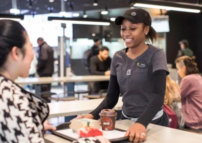 A smiling McDonald's employee serving a food tray with a meal and coffee to a customer