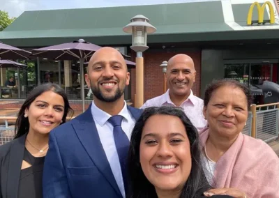 A smiling group of business professionals taking a group photo outside a McDonald's restaurant