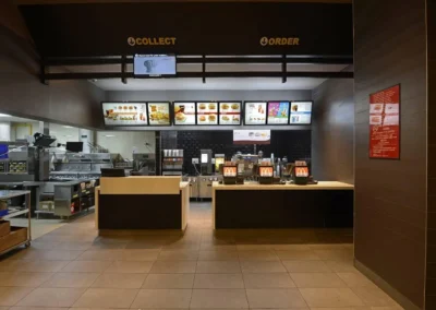 The front counter, order stations, and menu boards of an empty McDonald's service area
