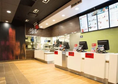 The interior of a modern McDonald's front counter with multiple register stations and menu screens