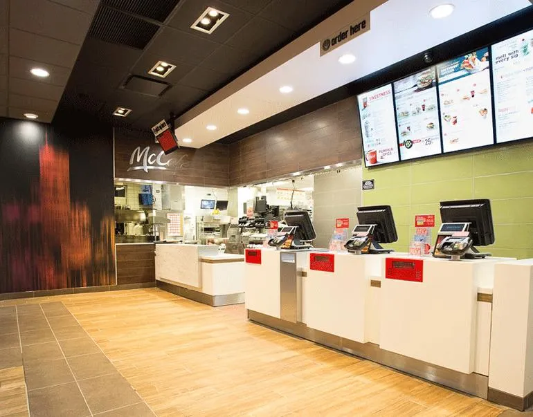 The interior of a modern McDonald's front counter with multiple register stations and menu screens