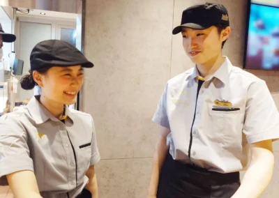 Two smiling McDonald's employees in uniform talking inside a restaurant