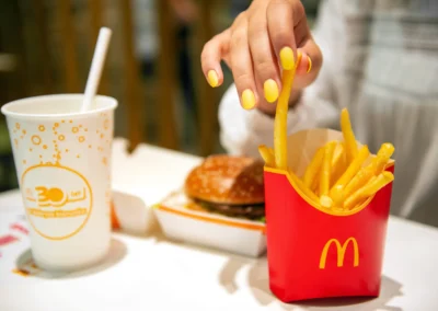 Woman with McDonald's French fries, burger and drink at table in cafe, closeup
